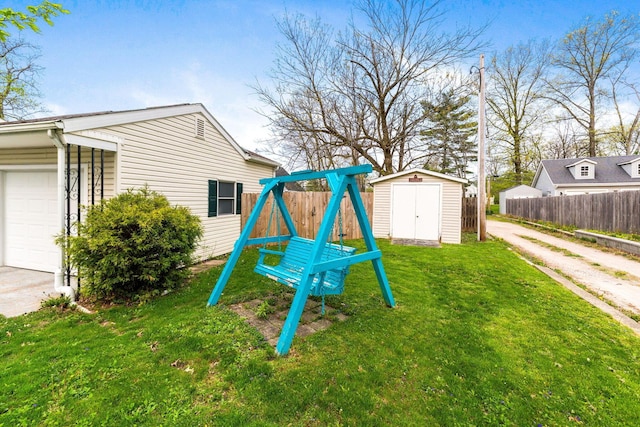 view of jungle gym featuring a yard, fence, an outbuilding, and a shed