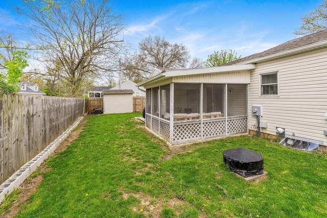 back of property featuring a sunroom, a fenced backyard, a storage unit, a yard, and a fire pit
