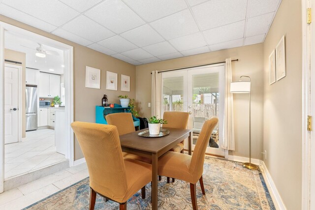 dining space featuring baseboards, ceiling fan, and a drop ceiling