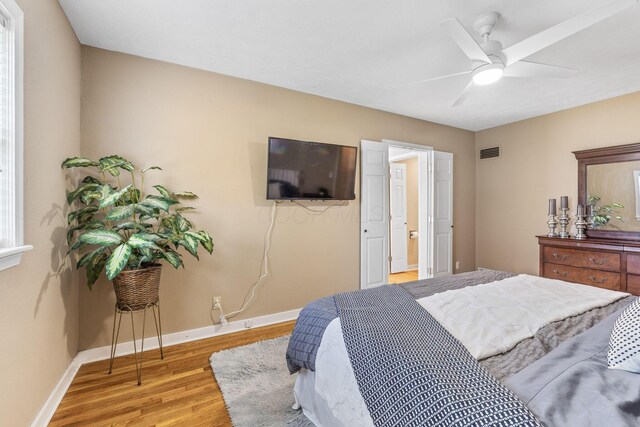 bedroom with ceiling fan, baseboards, visible vents, and wood finished floors