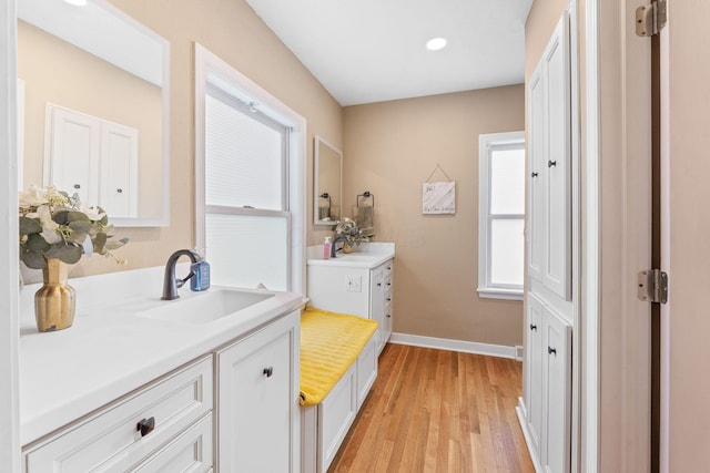 bathroom featuring a sink, recessed lighting, baseboards, two vanities, and wood finished floors