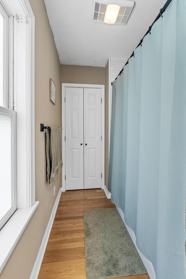 hall featuring visible vents, light wood finished floors, and baseboards