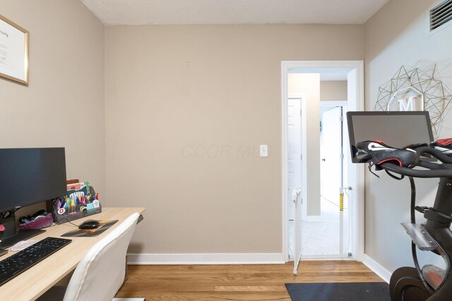 home office with visible vents, light wood-style floors, and baseboards