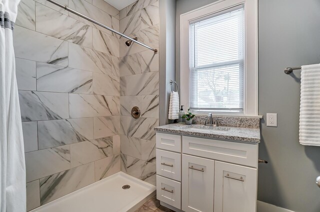 bathroom featuring tiled shower and vanity