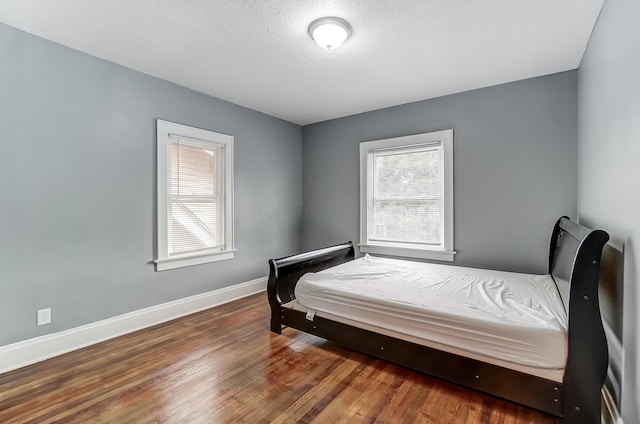 bedroom with baseboards and wood finished floors