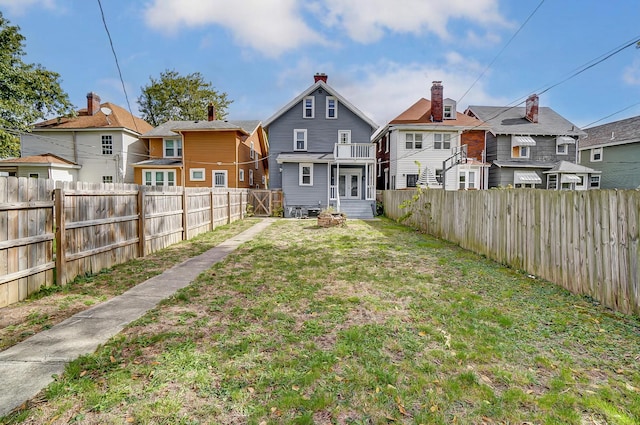rear view of property with a fenced backyard, entry steps, a yard, and a residential view