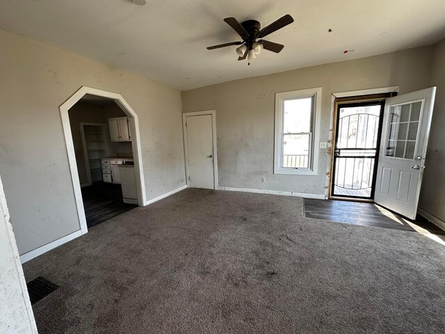 406 W Church St, Newark, OH 43055 - unfurnished living room featuring arched walkways, dark colored carpet, a ceiling fan, baseboards, and visible vents
