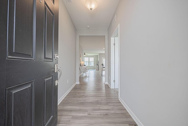 hallway featuring light wood-style floors and baseboards