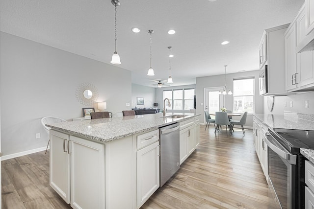 kitchen with a kitchen island with sink, appliances with stainless steel finishes, a sink, recessed lighting, and light wood-style flooring