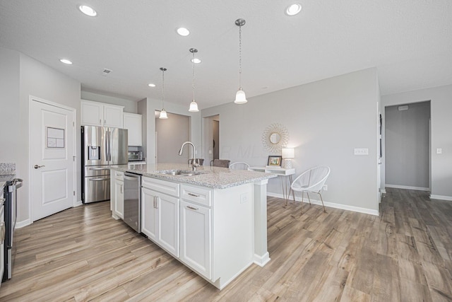 kitchen featuring white cabinets, appliances with stainless steel finishes, a sink, and light wood-style floors
