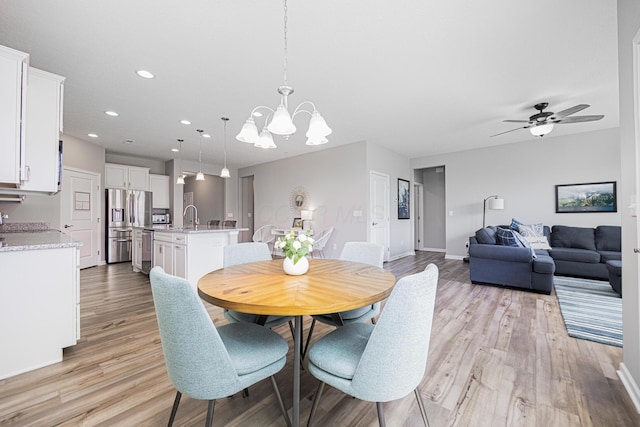 dining area with recessed lighting, light wood finished floors, ceiling fan with notable chandelier, and baseboards