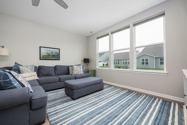 living room with a ceiling fan, baseboards, and wood finished floors