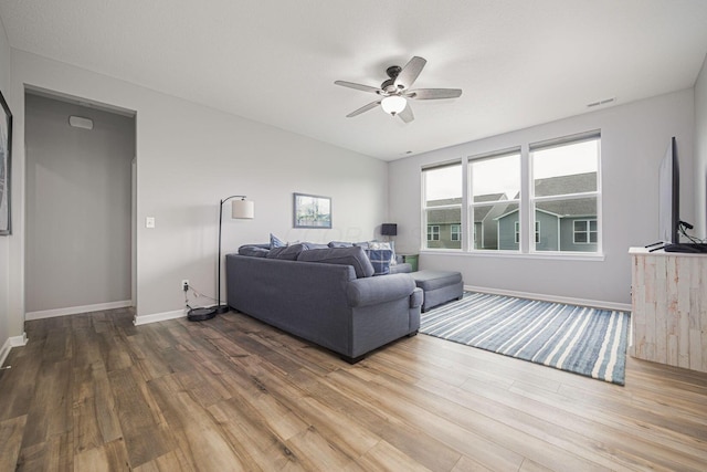 living area with visible vents, a ceiling fan, baseboards, and wood finished floors