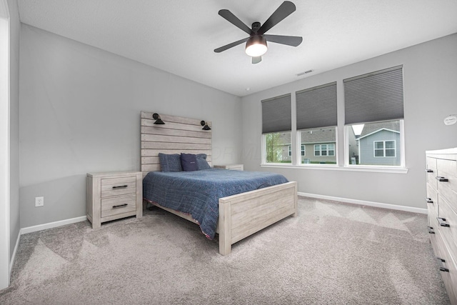 carpeted bedroom with baseboards, a ceiling fan, and visible vents