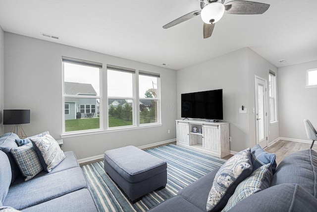 living area featuring visible vents, baseboards, ceiling fan, and wood finished floors
