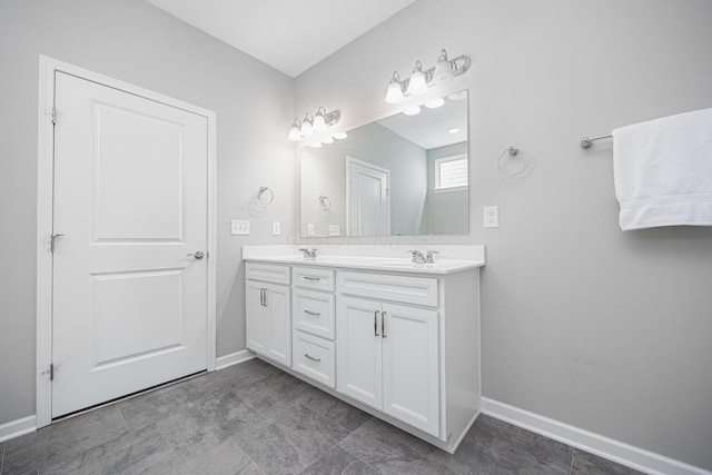 full bath with double vanity, baseboards, and a sink