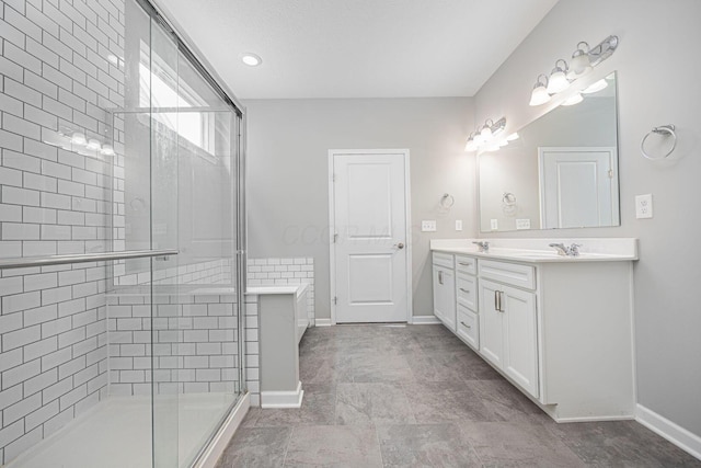 bathroom featuring baseboards, double vanity, a sink, and a stall shower