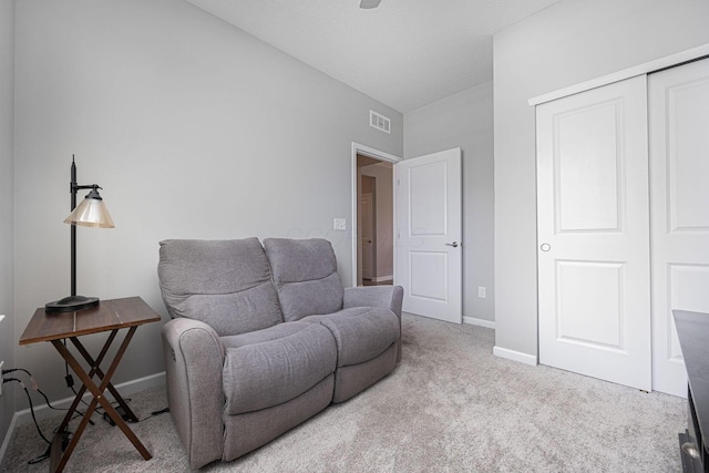 living area featuring baseboards, visible vents, and carpet