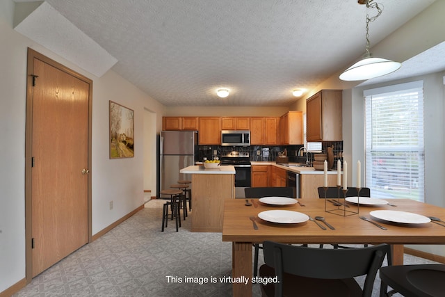 4207 Asbury Ridge Dr, Columbus, OH 43230 - kitchen with stainless steel appliances, light countertops, a sink, a center island, and a textured ceiling