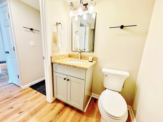 bathroom with toilet, baseboards, wood finished floors, and vanity