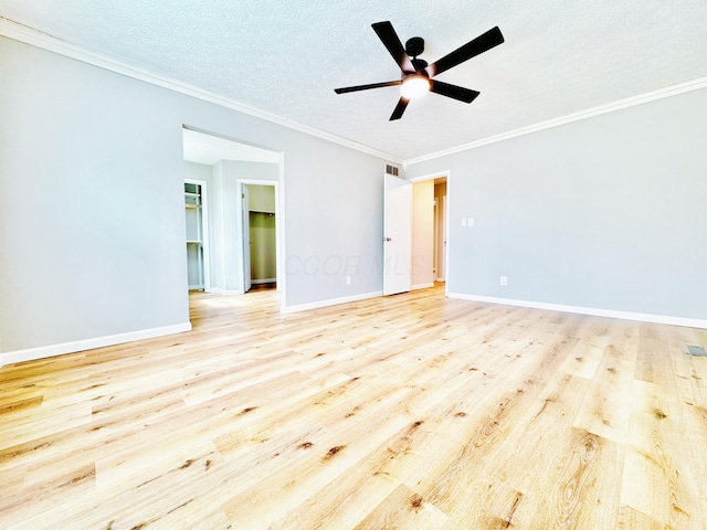 empty room with crown molding, ceiling fan, a textured ceiling, baseboards, and wood finished floors