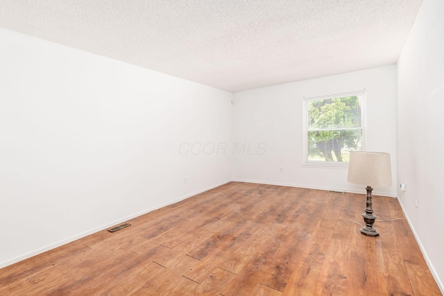 6556 Centennial Dr, Reynoldsburg, OH 43068 - unfurnished room with a textured ceiling, baseboards, visible vents, and wood finished floors