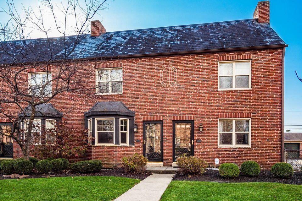 view of front of property featuring brick siding, a chimney, and a front lawn