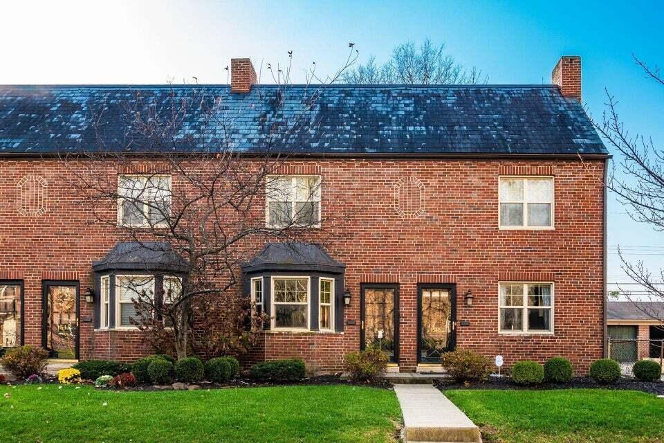 colonial home featuring brick siding, a chimney, and a front yard