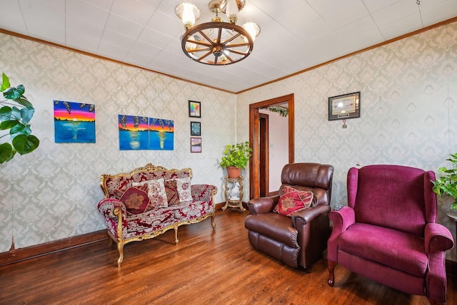 living area with ornamental molding, wallpapered walls, wood finished floors, and a notable chandelier