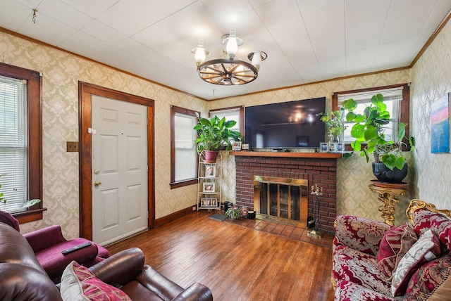 living room featuring crown molding, wood-type flooring, a brick fireplace, and wallpapered walls