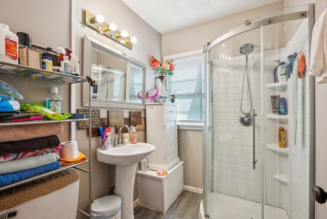 full bathroom featuring a stall shower, wood finished floors, and toilet