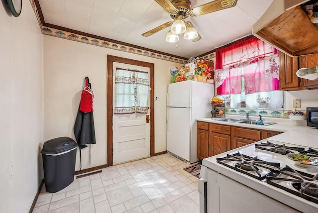 kitchen with a ceiling fan, white appliances, light countertops, brown cabinets, and a sink