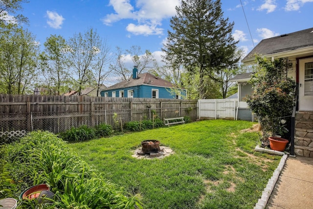 view of yard with a fenced backyard and a fire pit