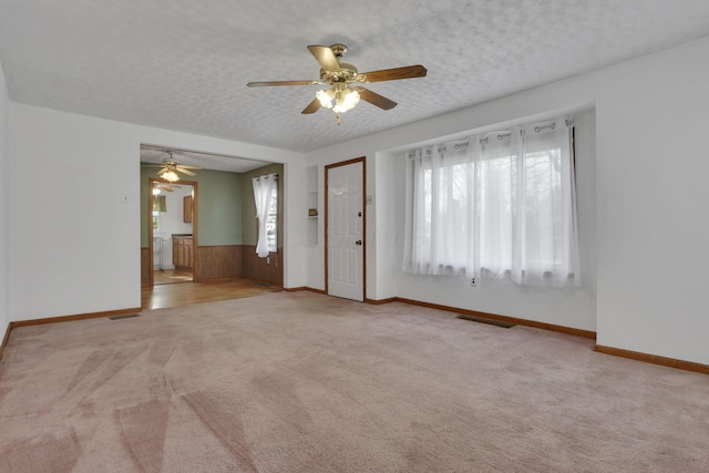 unfurnished room featuring carpet floors, a ceiling fan, a textured ceiling, and visible vents