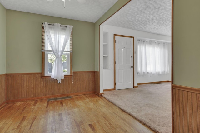 unfurnished room featuring wood walls and a wainscoted wall