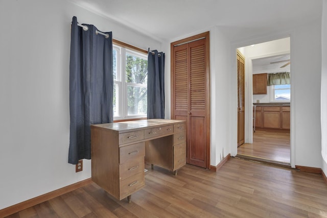 unfurnished office featuring baseboards and light wood-type flooring
