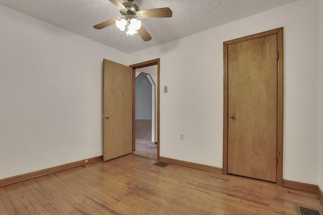 unfurnished room with baseboards, a ceiling fan, light wood-style floors, and visible vents