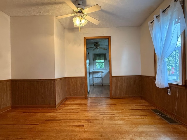 119 Highland Ave, Circleville, OH 43113 - spare room featuring wainscoting, light wood finished floors, ceiling fan, wood walls, and a textured ceiling
