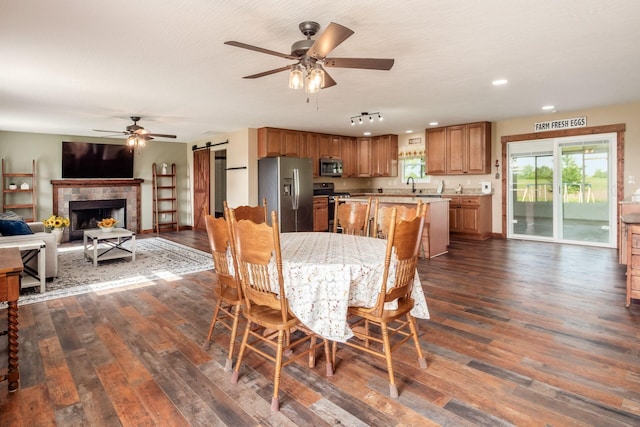 14140 State Route 56 SE, Mount Sterling, OH 43143 - dining space featuring a barn door, ceiling fan, dark wood-style floors, recessed lighting, and a tiled fireplace