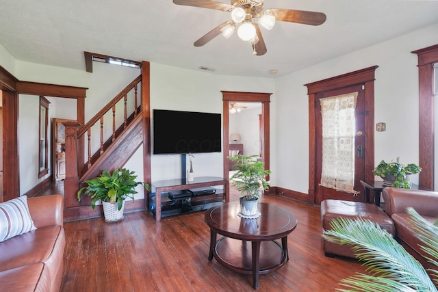 living area with a ceiling fan, baseboards, wood finished floors, and stairway