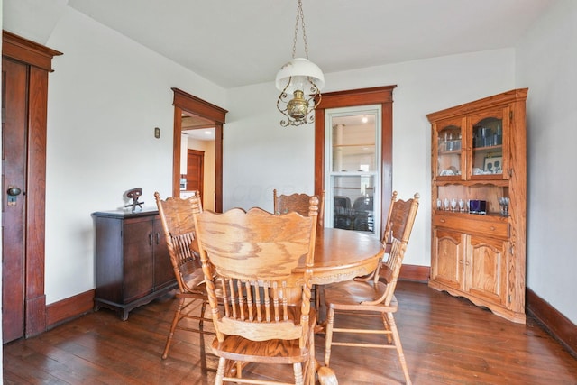 dining area featuring dark wood-type flooring, baseboards, and a chandelier