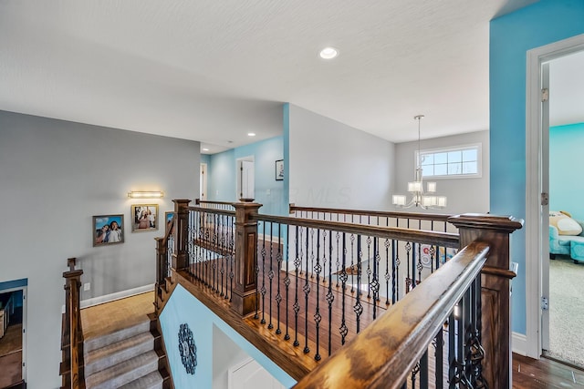 hallway featuring wood finished floors, baseboards, recessed lighting, a chandelier, and an upstairs landing