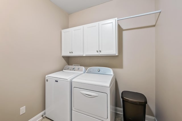 clothes washing area with separate washer and dryer, cabinet space, and baseboards