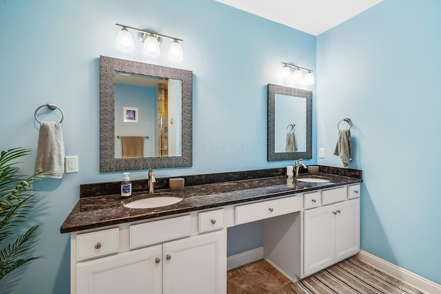 bathroom featuring double vanity, a sink, and baseboards