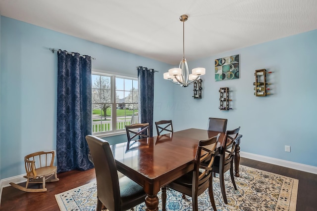 dining area featuring an inviting chandelier, baseboards, and wood finished floors