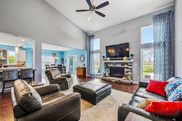 living area featuring high vaulted ceiling, a wealth of natural light, ceiling fan, and dark wood-type flooring