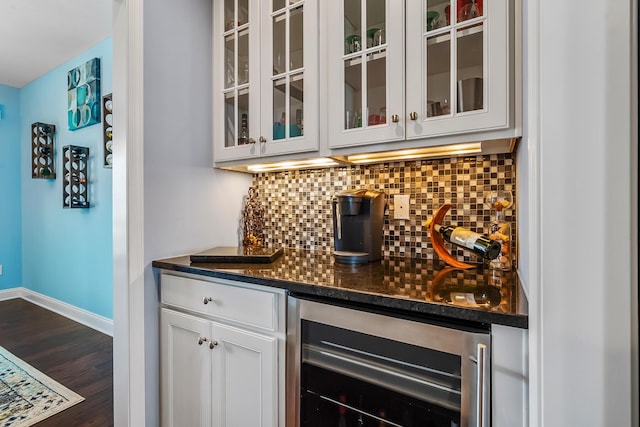 bar with tasteful backsplash, dark wood finished floors, baseboards, beverage cooler, and bar area