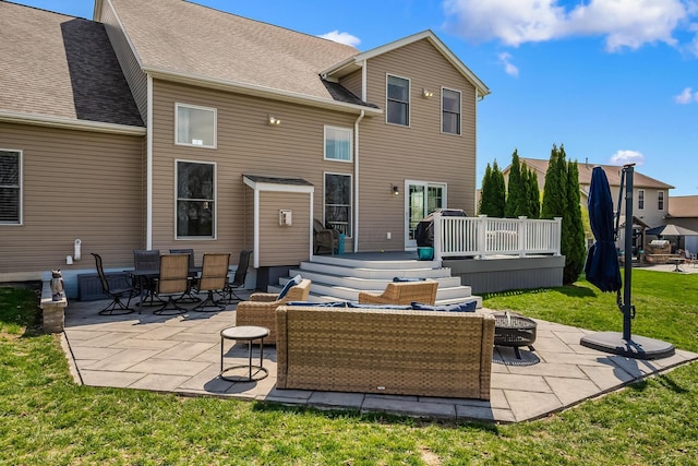 rear view of house with a shingled roof, an outdoor fire pit, a deck, a patio area, and a yard