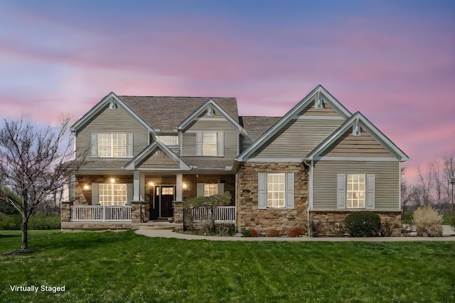craftsman inspired home with a porch, a front lawn, and stone siding