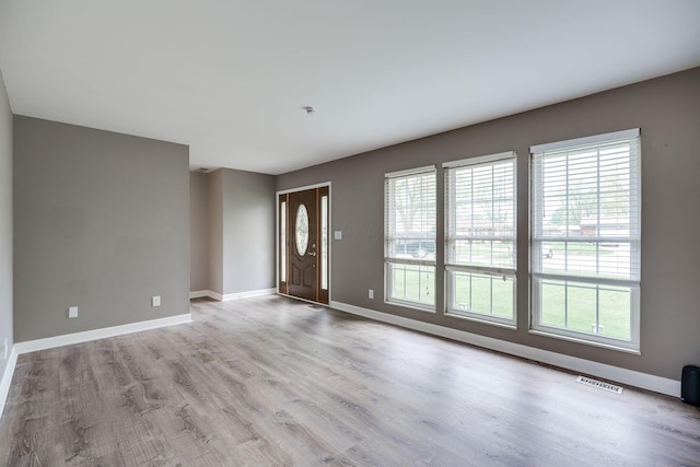 interior space featuring visible vents, baseboards, wood finished floors, and a healthy amount of sunlight
